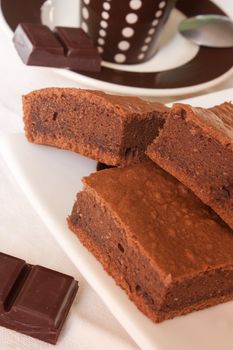 Pieces of chocolate cake on a plate with a cup of coffee in background