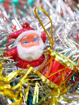 Doll of Santa Claus with a red drum against a tinsel