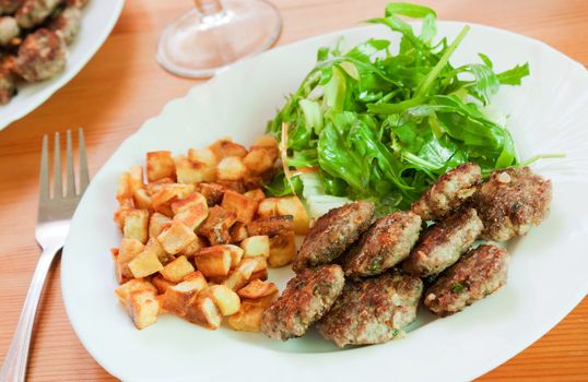 Meatballs with beef and spices, fries potatoes and salad 