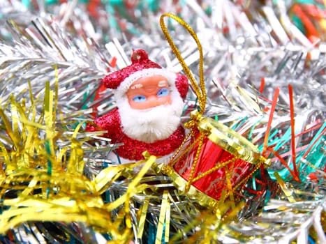 Doll of Santa Claus with a red drum against a tinsel