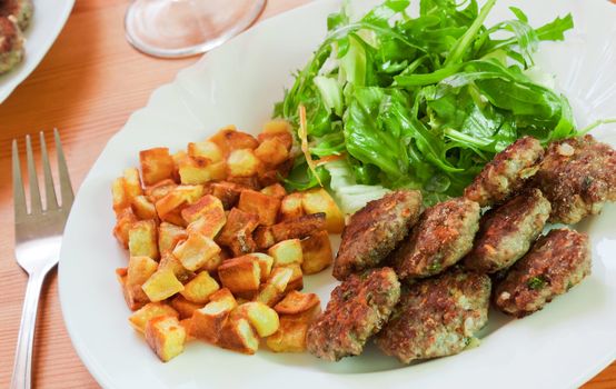 Meatballs with beef and spices, fries potatoes and salad 