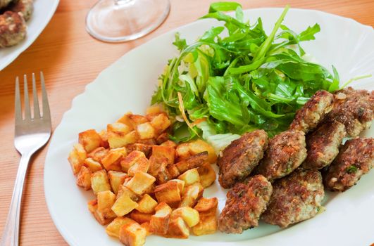 Meatballs with beef and spices, fries potatoes and salad 