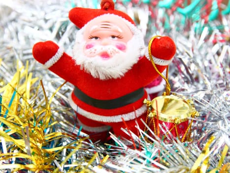 Doll of Santa Claus with a red drum against a tinsel