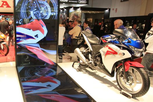 People trough Honda motorcycles exhibition area at EICMA, International Motorcycle Exhibition in Milan, Italy.