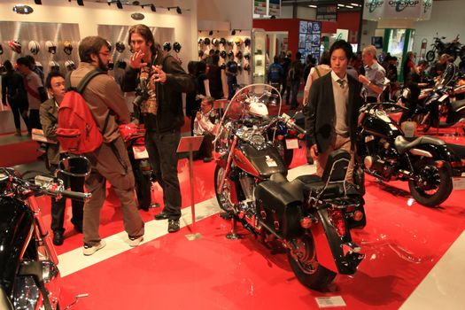 People trough Moto Guzzi motorcycles exhibition area at EICMA, International Motorcycle Exhibition in Milan, Italy.