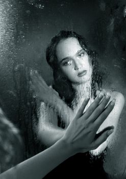 Portrait of the woman in reflection of a wet mirror