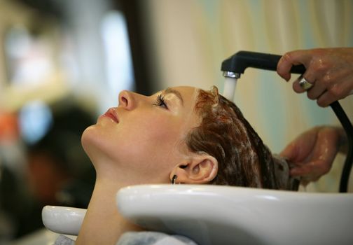 Barber makes a hair-dress to the young brunette