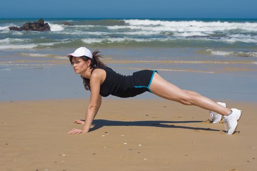 Fitness model doing push up exercises on the beach