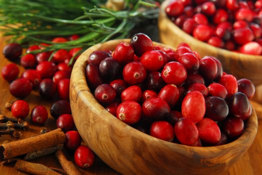 Fresh red cranberries in wooden bowls with spices and pine branches