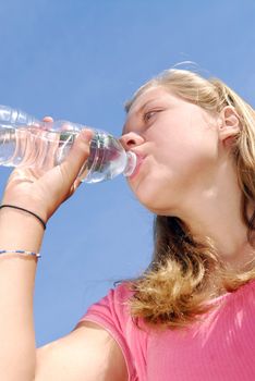 Young girl drinking water from clear plastic bottle