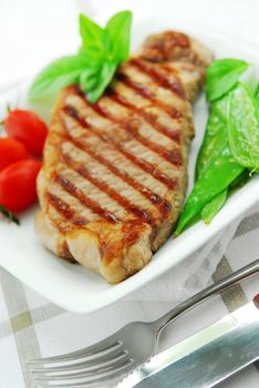 Grilled New York beef steak served on a plate with vegetables