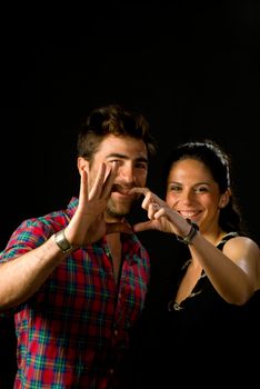 Smiling young couple making a heart gesture