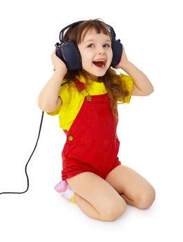 A little girl sitting on a white background with large earpieces