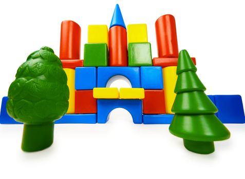 Toy colored castle and plastic trees isolated on white background