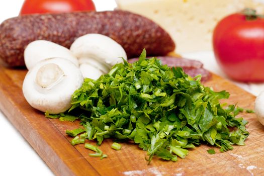 Some ingredients for pizza: parsley, sasuage, tomatoes.