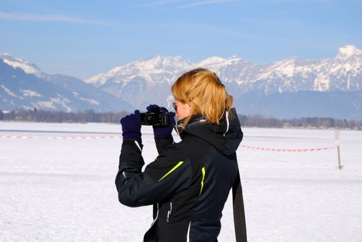 Woman with camcorder filming panorama of austrian winter.