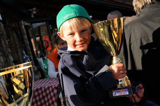 KAPRUN AUSTRIA - MARCH 5: Maiskogel Fanlauf 2011. Unidentified boy holding his trophy at charity ski race with many celebrities in austria on March 5, 2011 at the Maiskogel in Kaprun, Austria