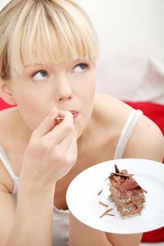 Beautiful woman sitting on couch and eating chocolate cake.