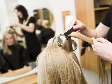 Hairdresser in action with blond customer close up