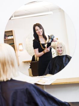 Hairdresser in action with blond customer