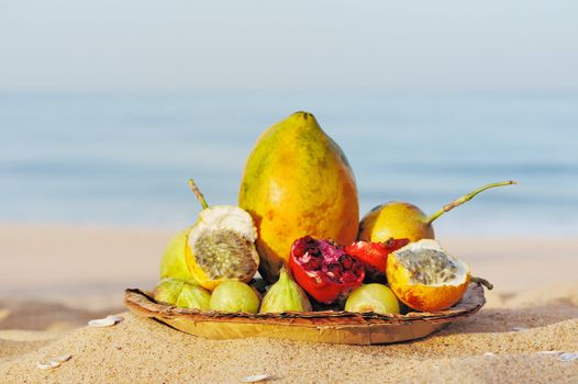 Exotic tropical fruit on the leaves plate, on the sandy beach