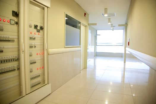 A hospital hallway with an electronics cabinet and bright window