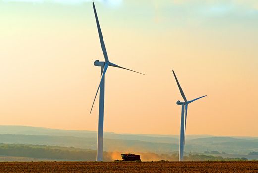 a combine harvester between two wind turbines