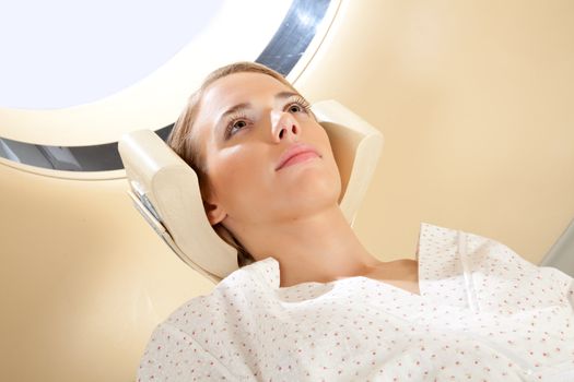 A young woman with eyes open preparing for a CT scan