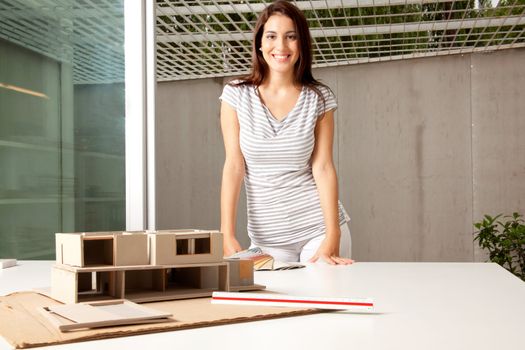 A young architect in an office with a rough model of a house
