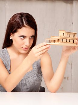 An architect designer examining a rough model house of wood