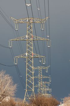 High voltage electricity line against dark overcast sky