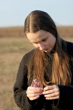 Girl standing in a field holding a flower