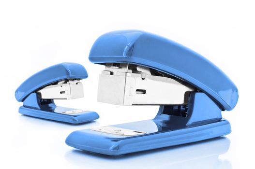 Close up of two blue office staplers isolated over white