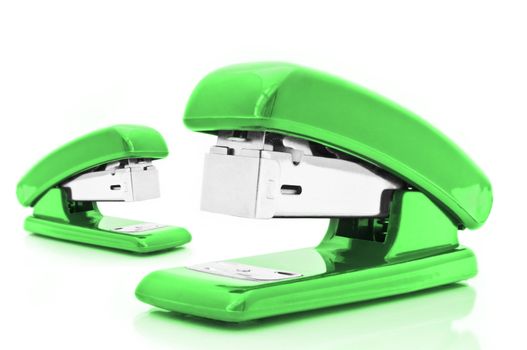 Close up of two green office staplers isolated over white
