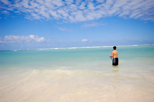 Man is fishing on An exotic beach with white sand, the sky is blue with clouds. Dominican Republic, Punta Cana.