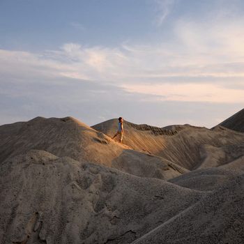 young man go up in sand desert in sundown silhouette