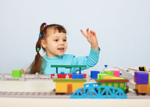 A child plays with a toy railroad on table