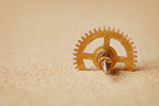 Clock detail - a gear in the sand close up
