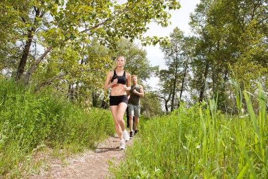 Young friends jogging together outdoors on a trail