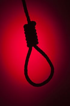 Silhouetted Hangman's Noose Over Red Spot Lit Background.