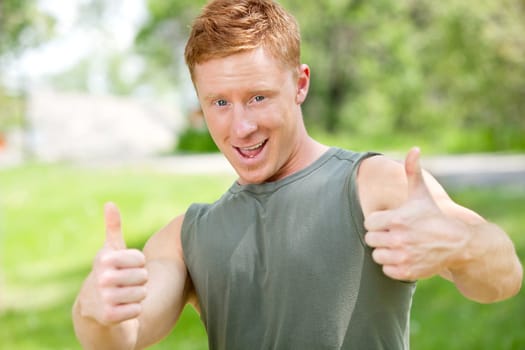 Portrait of a man showing thumbs-up sign against blur background