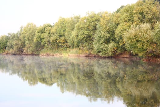blue lake with colorful wood and blue sky in autumn