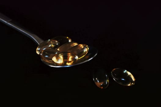 A spoonful of gel pills on a black background