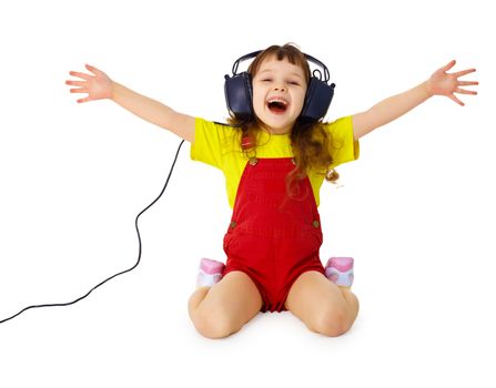 A happy little girl listens to music with headphones isolated on white background