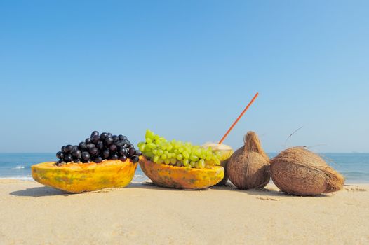 Papaya, coconut, nut and grapes on the sand