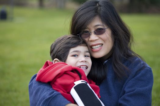 Beautiful asian mother holding her disabled son at park