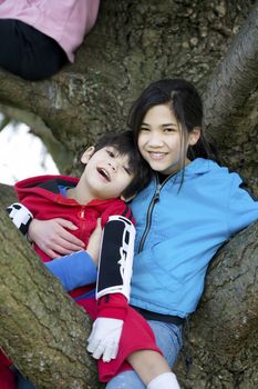 Sister holding disabled brother in tree