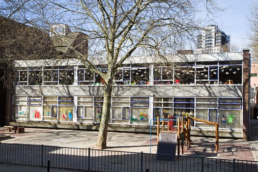 Streetview in city with Infant school or Kindergarten and school yard on day in early spring