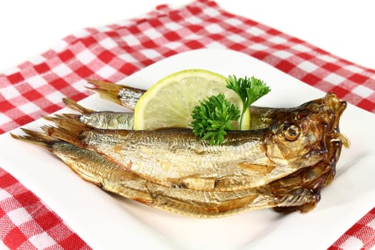 fresh smoked sprats on a white plate