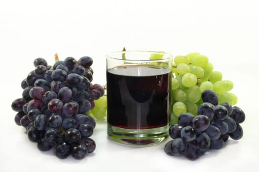 a glass of grape juice with light and dark grapes